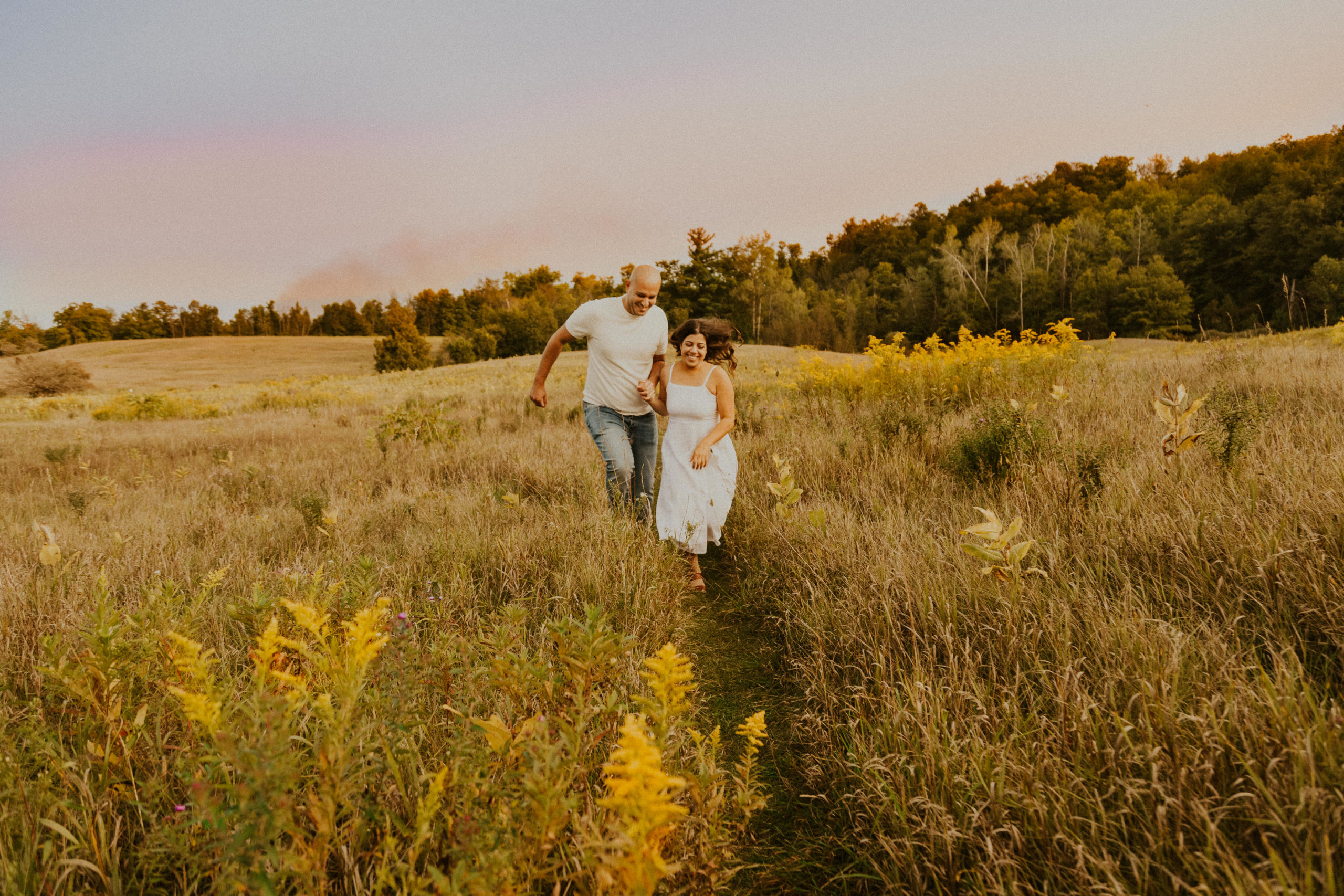 Golden Hour Engagement Session Georgetown, Ontario. Couple running through fields at sunset.