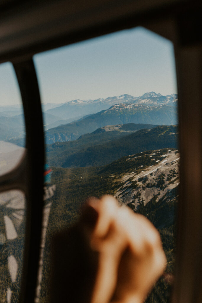 Couple holding hands in helicopter during their heli elopement in Whistler, British Columbia.