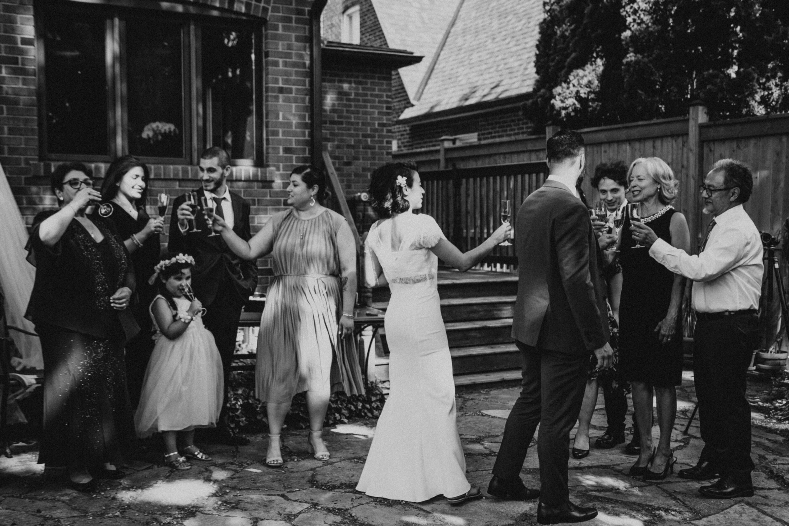 Couple toasting with their family at their backyard elopement reception in Toronto, Ontario.