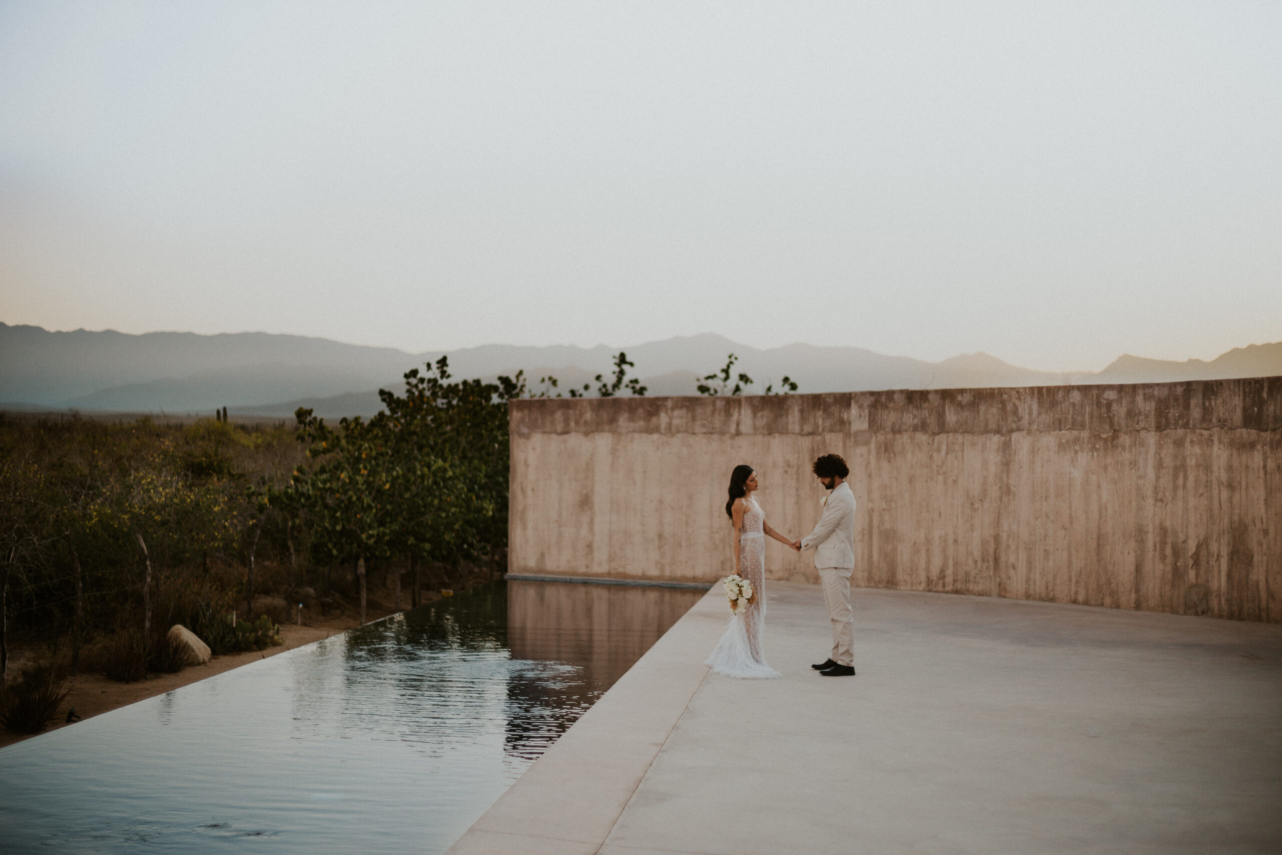 Couple eloping at sunrise by the pool, overlooking the desert at Paradero in Todos Santos, Mexico.