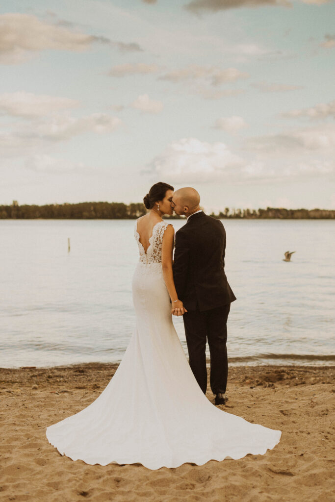 Couple kissing on their elopement day by the water at Cherry Beach in Toronto.